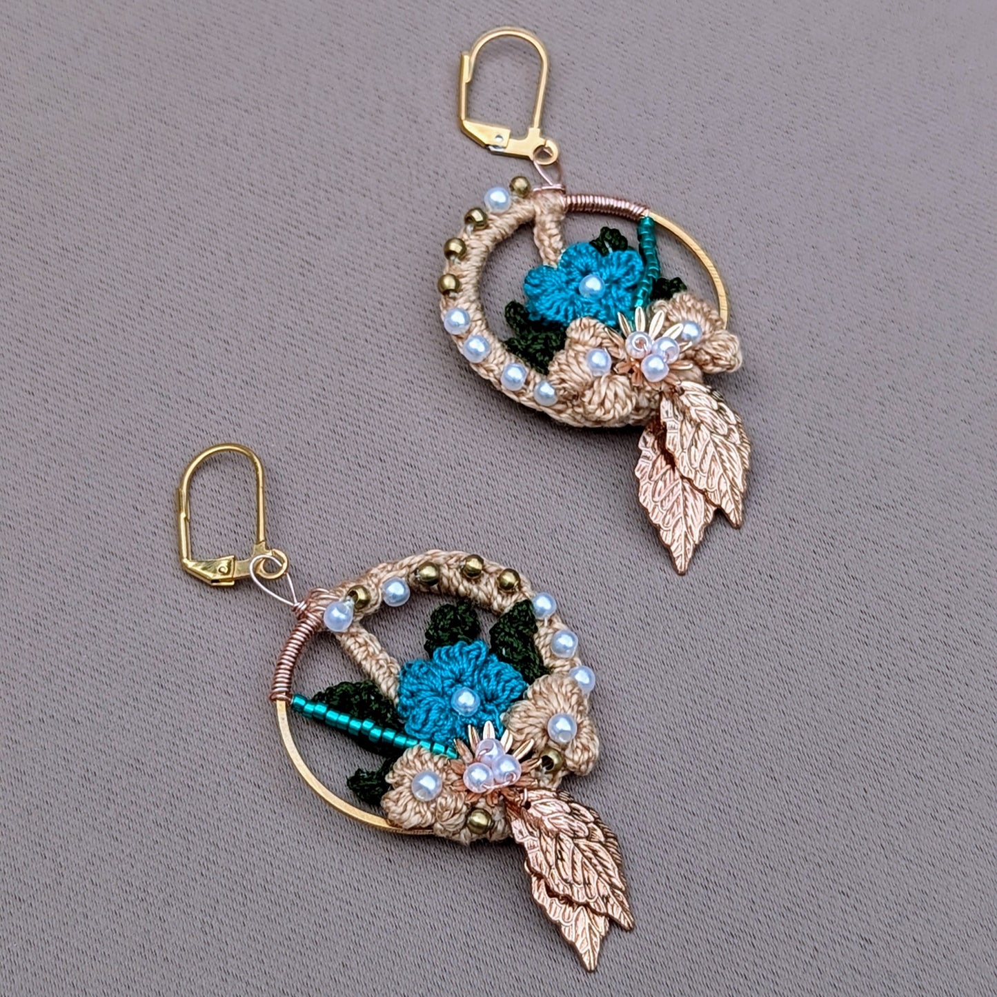 Discover a unique pair of artisan-crafted Indian-inspired earrings, exclusively from Mayaani Jewellery, a sustainable UK brand. These earrings feature intricate woven solid brass, seed pearls, and blue beads, enhanced by gold, blue, and dark green crochet floral motifs. Lightweight and comfortable, they are perfect for everything from weddings and special occasions to everyday wear.