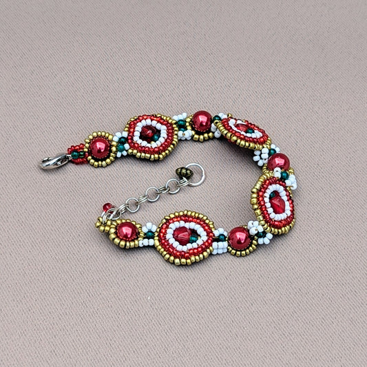 An exclusive handcrafted bracelet in vibrant red, green, gold, and white beads, available only from the sustainable UK brand Mayaani Jewellery. This unique accessory features a combination of new and high-quality upcycled glass beads arranged in artistic circles inspired by the festive season. It comes with an adjustable clasp and a lovely pair of teardrop earrings made with red, bronze, and seed pearls. Experience the allure of lightweight modern designs infused with traditional craftsmanship.
