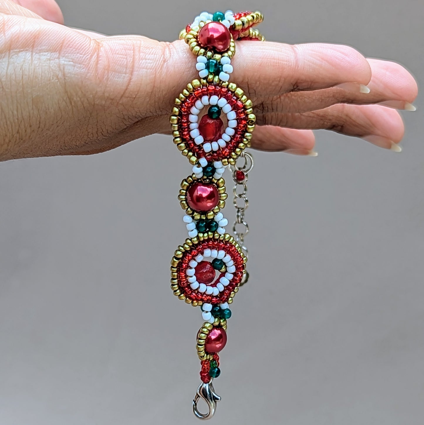 Full view of adjustable red, gold and white handcrafted bracelet with extender chain and secure clasp closure.