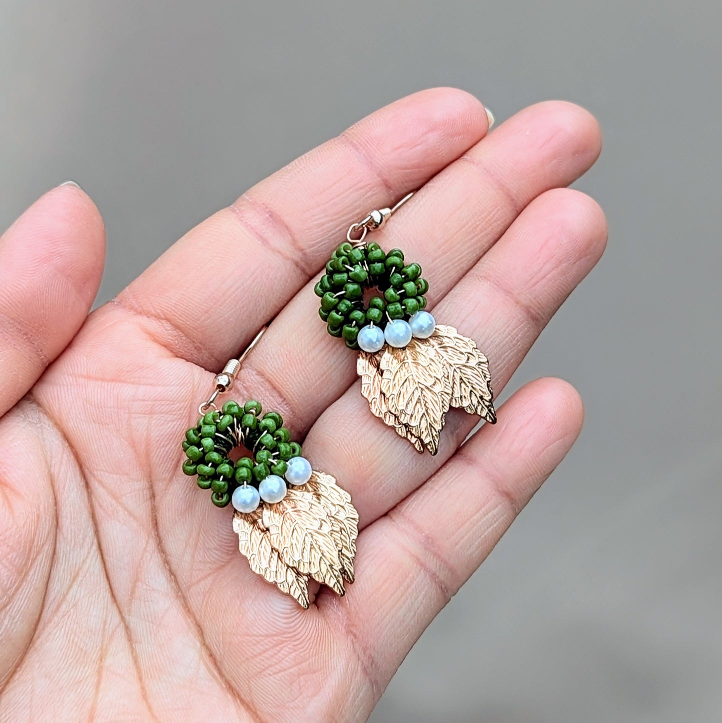 Experience the beauty of nature inspired jewellery with these unique handcrafted earrings by Mayaani Jewellery UK. Featuring a green circular bead design with seed pearl accents and gold leaf charms for modern Indian inspired jewellery with your comfort in mind.
