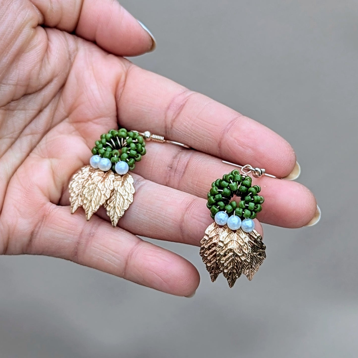 Exceptionally lightweight one of a kind handcrafted earrings featuring a circular design of green beads, seed pearl accents and detailed gold leaves. Exclusive to sustainable UK brand Mayaani Jewellery, this pair of earrings celebrates nature inspired motifs with modern artistic design and delicate craftsmanship.