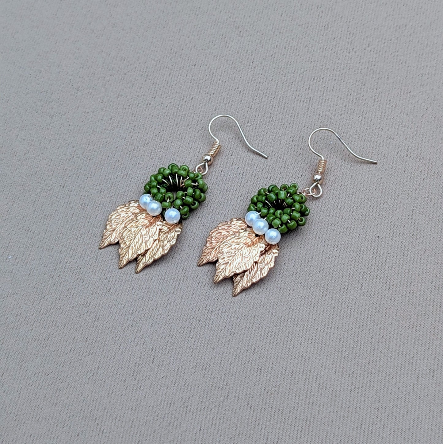Nature inspired earrings by sustainable UK Indian brand Mayaani Jewellery featuring a circular green beaded hoop with ivory seed pearl accents and gold leaf charms.