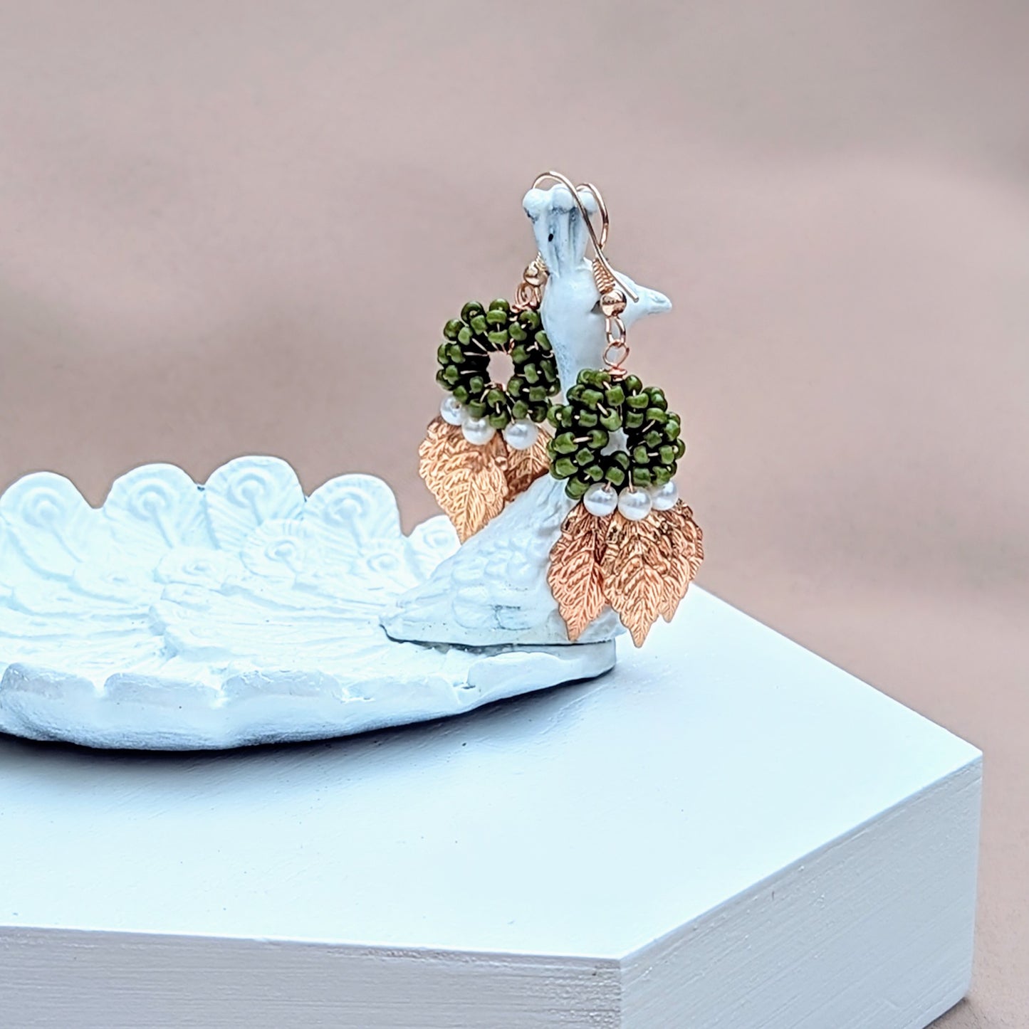 A pair of handcrafted earrings from sustainable brand Mayaani Jewellery, showcasing a green beaded circular motif embellished with seed pearls and delicately engraved gold leaves. These earrings bring together modern design and intricate craftsmanship.