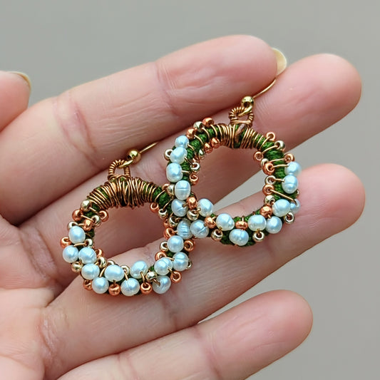 A unique limited edition design pair of artisan handcrafted natural freshwater pearl earrings exclusive to Mayaani Jewellery UK. Featuring delicate green hand crochet, antique bronze wire wrapping and gold hand beadwork arranged in a circular pattern finished with a pair of gold plated stainless steel earring hooks. A brilliant Indian-inspired twist on classic pearl earrings perfect for your special occasions and more.