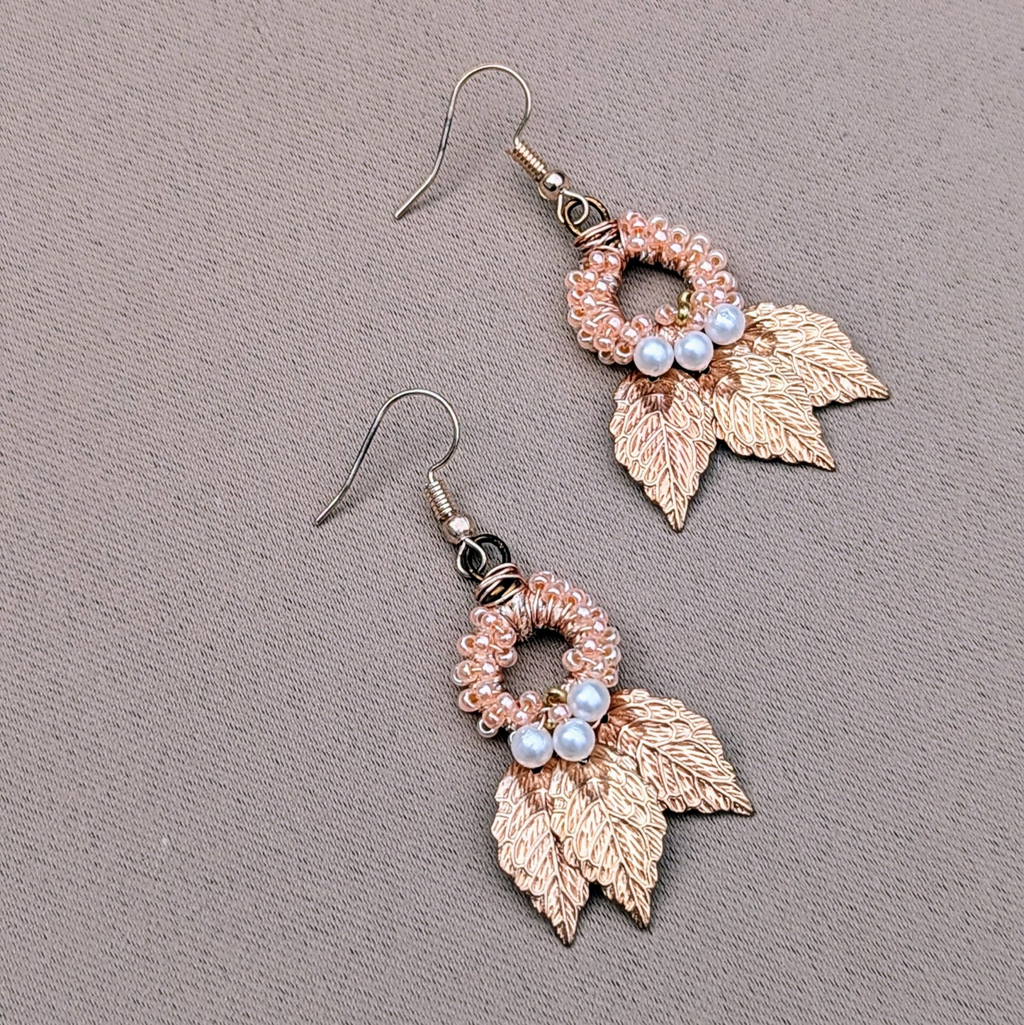 Limited edition Indian Boho earrings by Mayaani Jewellery, featuring gold-plated leaves and handcrafted details. The design blends hand-crocheted peach beads with wire work and seed pearls, reflecting sustainable craftsmanship. Made by a UK brand known for creating eco-conscious accessories, these earrings embrace elegance with a bohemian twist.
