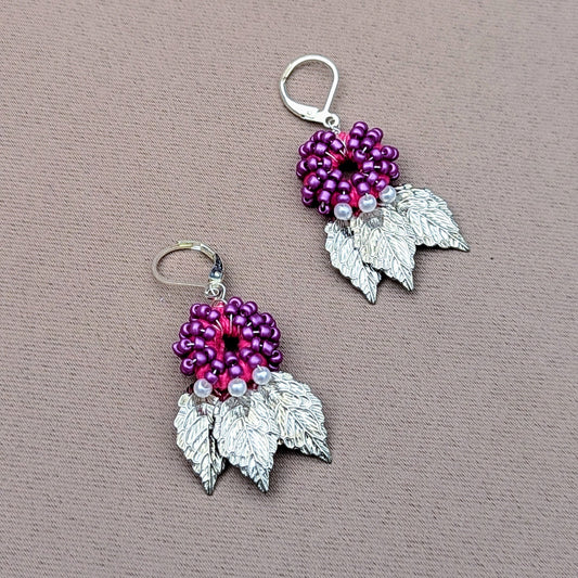 Experience nature inspired elegance everyday in these limited edition design handcrafted earrings exclusive to sustainable UK brand Mayaani Jewellery. Featuring a circular design of pink hand crochet, hand wrapped silver plated copper wire and lustrous purple and pearl seed beads  and stainless steel silver leaf charms. Finished with luxurious 925 stamped sterling silver lever back hooks they the perfect pair of modern sophistication for everything from weddings and special occasions through to everyday.