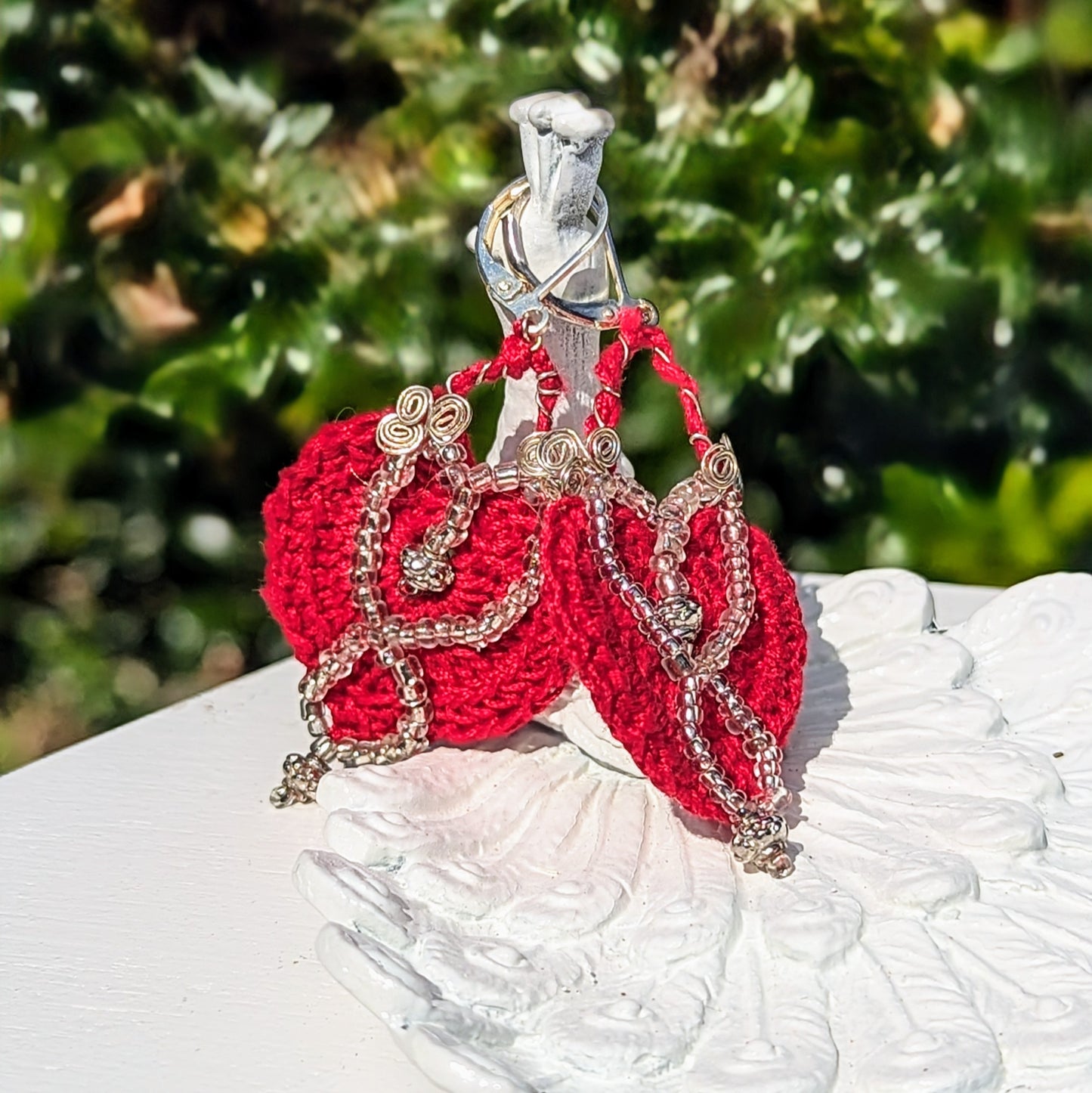 Bohemian-style heart earrings photographed outdoors, glowing in natural light and showcasing their vibrant craftsmanship.