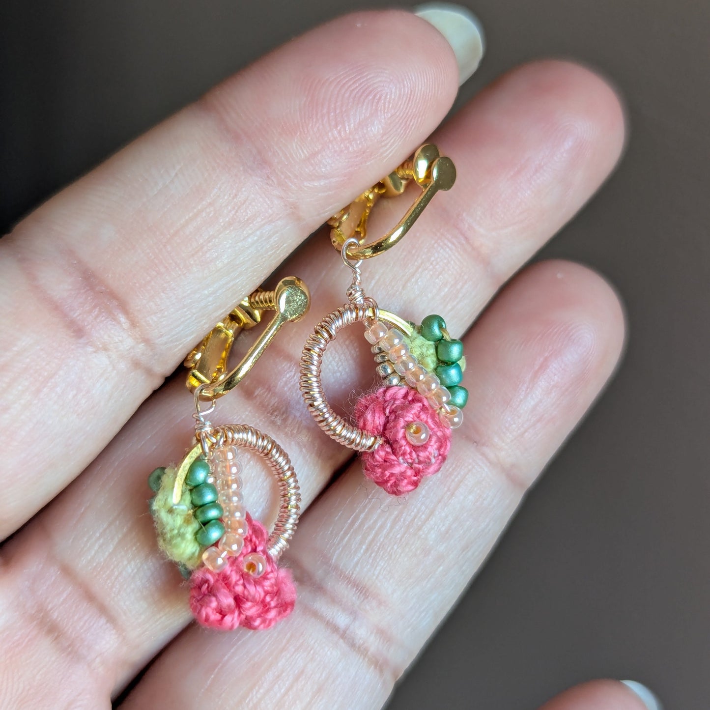 Mayaani Jewellery handcrafted Anandi clip-on earrings in green, pink, and gold displayed held in hand - comfortable, playful elegance for every woman.