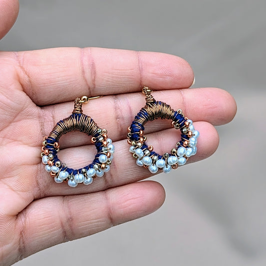 Close-up of handcrafted hoop earrings by Mayaani Jewellery UK featuring natural freshwater pearls, copper tones, and deep blue seed beads in a sustainable design.