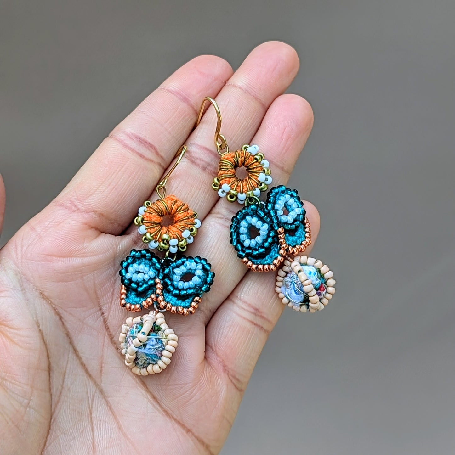 Artisanal blue butterfly earrings, held in a hand, handcrafted by Indian design, with upcycled vintage seed beads, crochet work, and a handcrafted scrap bead drop. Created by sustainable UK jewellery brand Mayaani Jewellery.