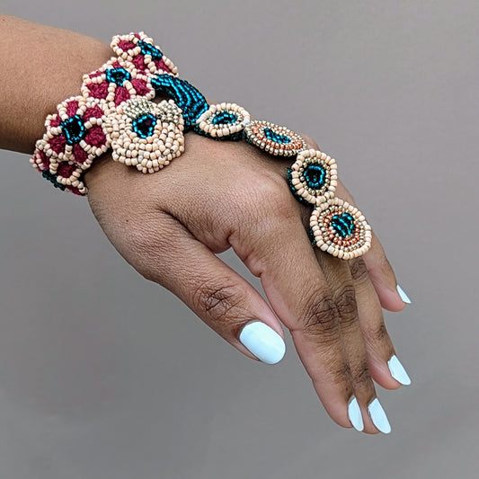 Hand wearing a handmade Indian bridal haath phool bracelet from the Neha Collection, featuring emerald green, gold, red and peach beadwork, artisan crafted in the UK.