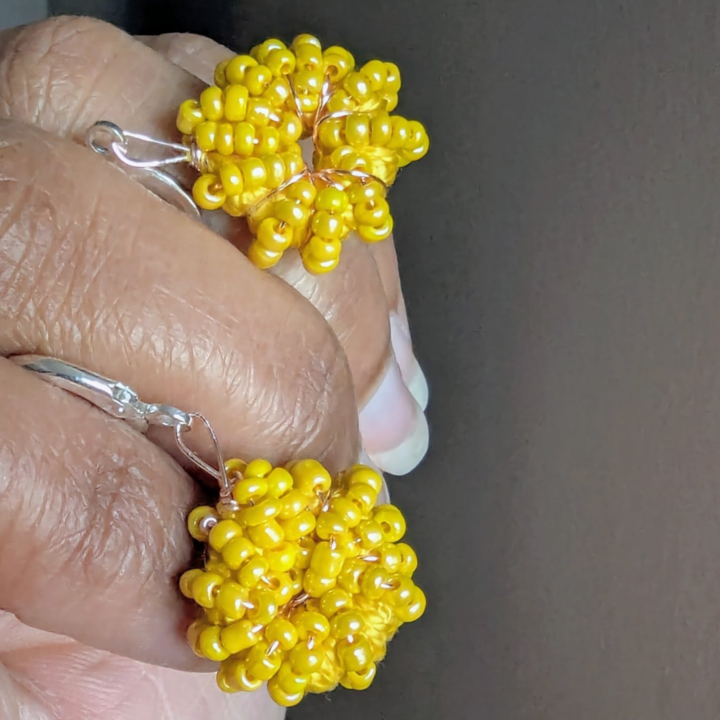 Hand holding artisan handmade summer yellow hoop earrings handcrafted in the UK, one-of-a-kind & Indian heritage inspired.