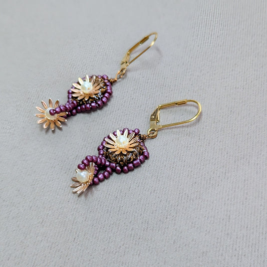 Side view of Sitara earrings - circular bronze crochet element edged with purple glass beads and accented with gold flowers and vintage seed pearls.