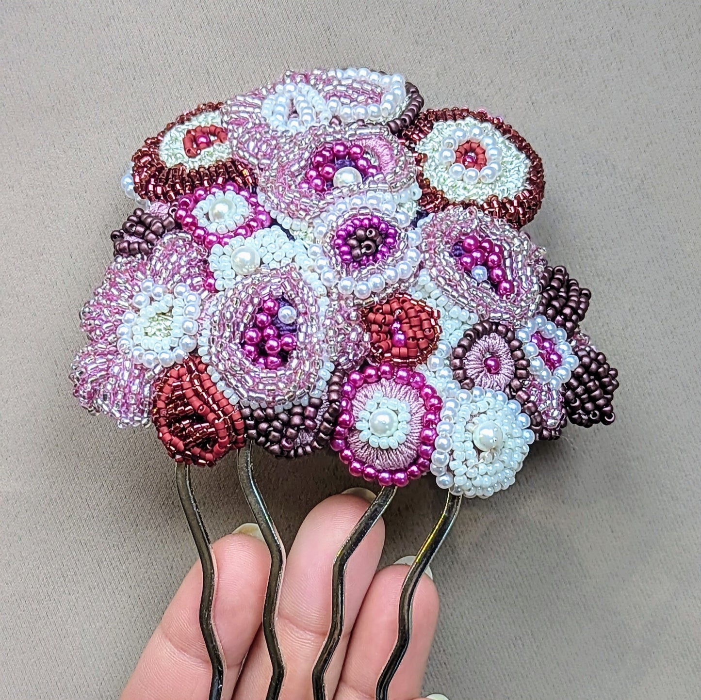 A close-up of the Gulab Rani bridal hair comb by Mayaani Jewellery, handcrafted using delicate glass seed beads and bead embroidery techniques. The floral design features layered concentric circles and is set on a four-pronged stainless steel pin, blending modern craftsmanship with Indian heritage artistry.