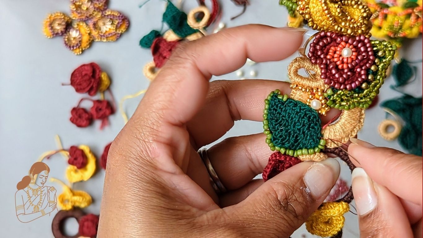 Work-in-progress shot of handcrafted floral necklace in vibrant beads and crochet being hand sewn reflecting Mayaani Jewellery's slow, sustainable creative process.
