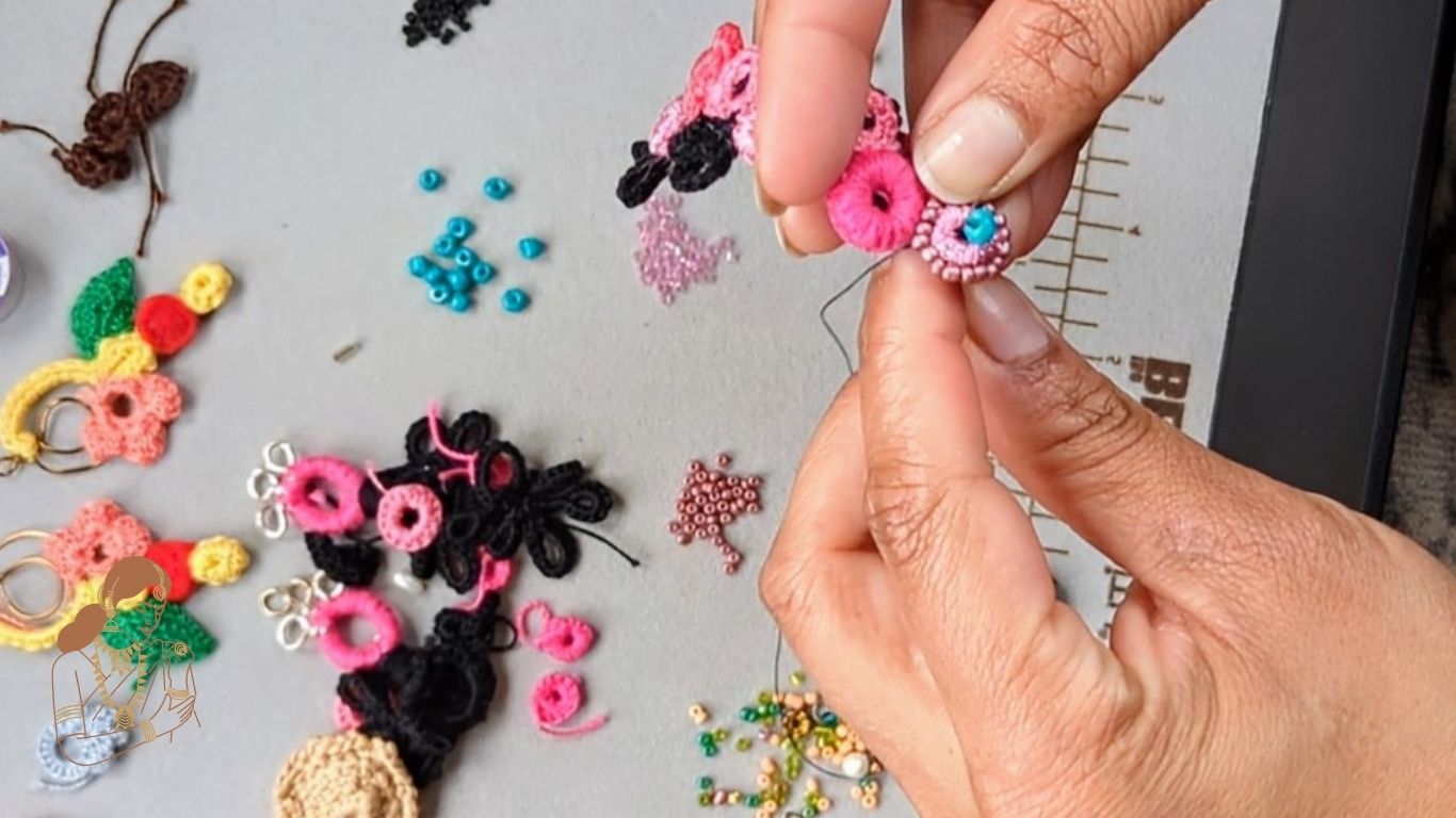 Close up of hands crafting a bead, crochet piece of pink, black and blue jewellery at the Mayaani Jewellery studio in the UK where the focus remains on celebrating heritage through slow, sustainably handcrafted jewellery.