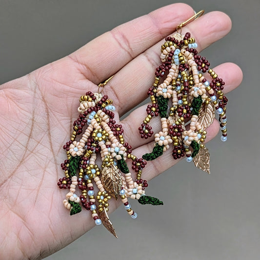 Detailed photo of Mayaani's one-of-a-kind Aishwarya bridal occasion earrings, showcasing multiple seed bead strands with rose, green, and pearl tones, anchored by crochet work and finished with gold-plated accents.
