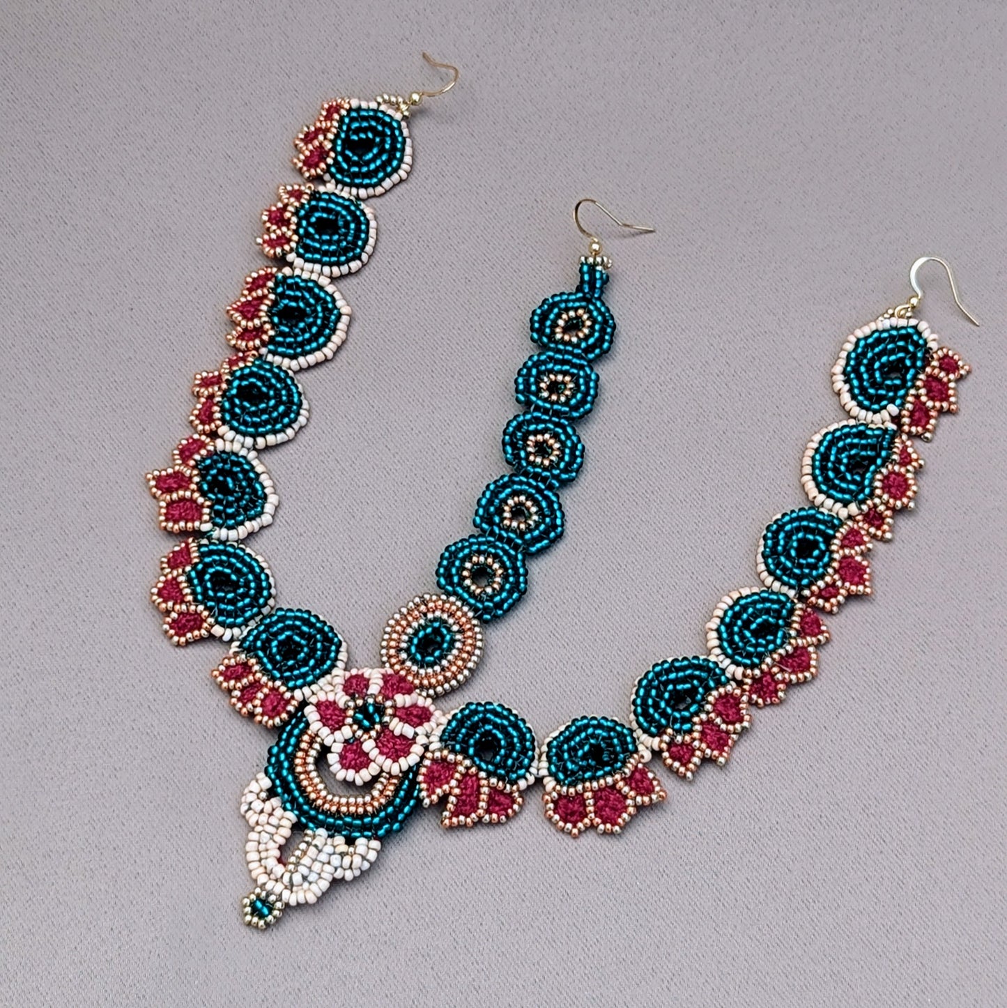 Handcrafted maang tikka bridal set in emerald green, red, and gold tones, designed with floral beadwork and intricate wire wrapping, part of the Neha Collection by Mayaani Jewellery UK.