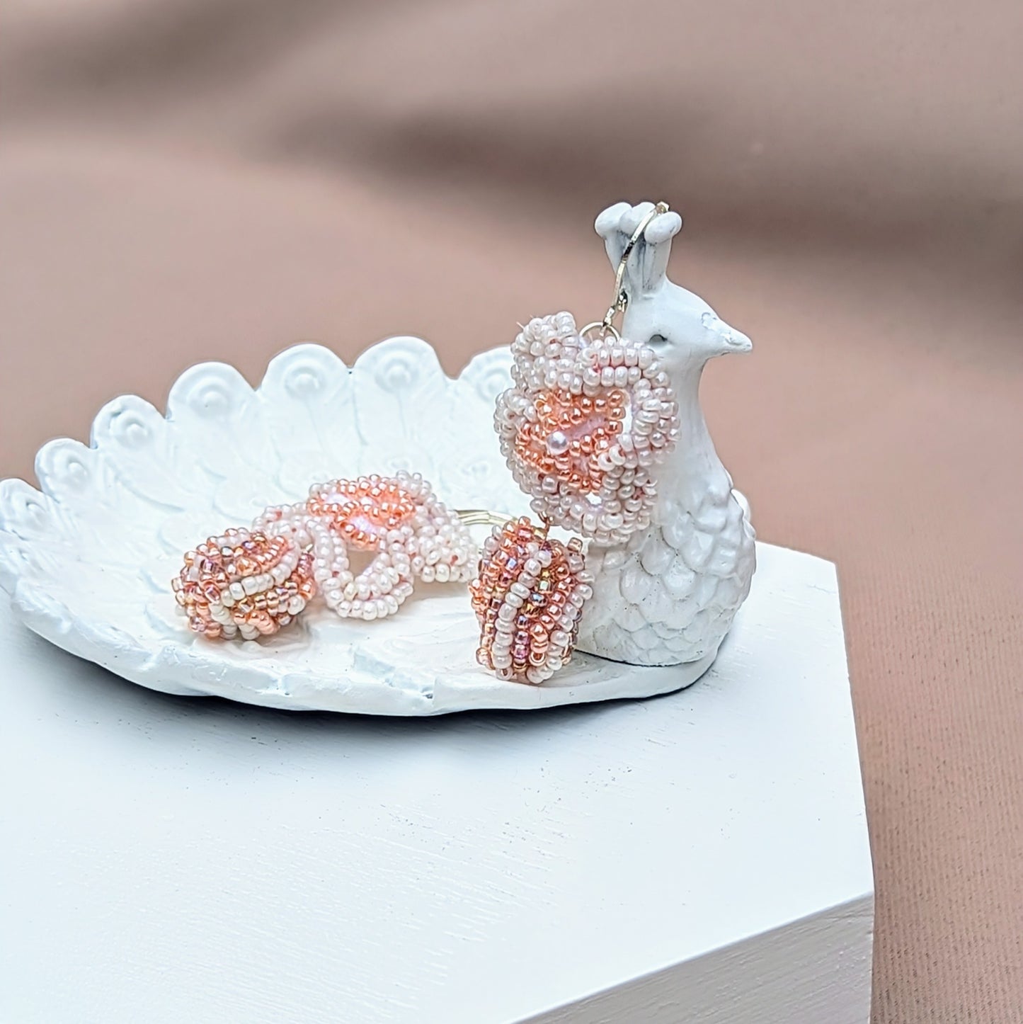 Close-up of one-of-a-kind bridal earrings made with white and peach seed beads, floral crochet detailing, and a unique scrap bead, designed by sustainable Indian brand Mayaani Jewellery.