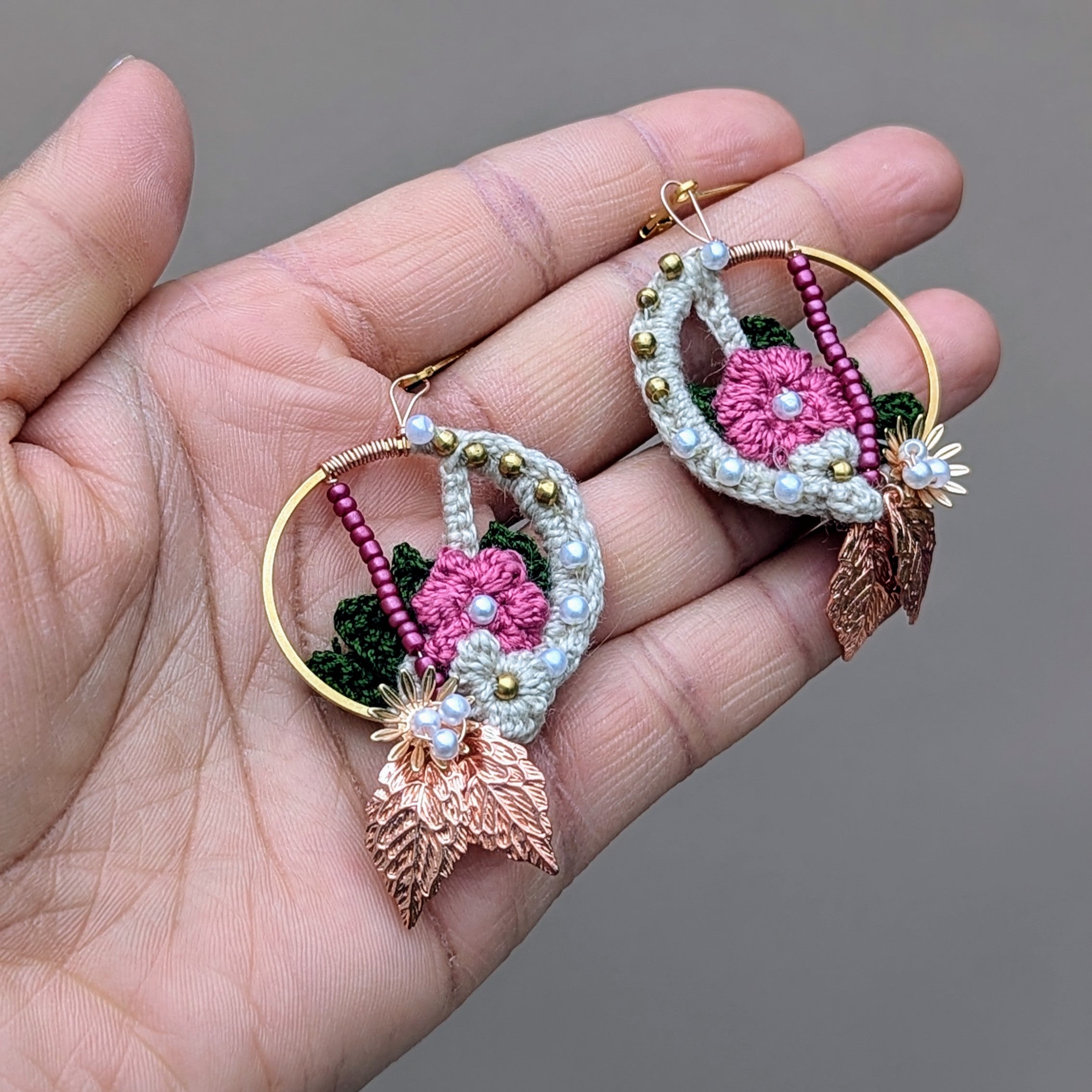 Three one-of-a-kind, Indian inspired hoop style earrings by Mayaani Jewellery in pink and green featuring floral crochet, seed pearls, solid brass beads, wire wrapping details and gold leaf accents.
