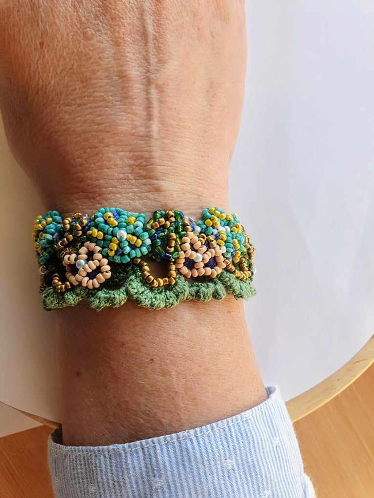 Mayaani Jewellery custom metal free artisan handcrafted floral beaded bracelet featuring intricate blue, gold, and blush seed bead flowers on a green crochet base handcrafted for Clare - real life customer review.