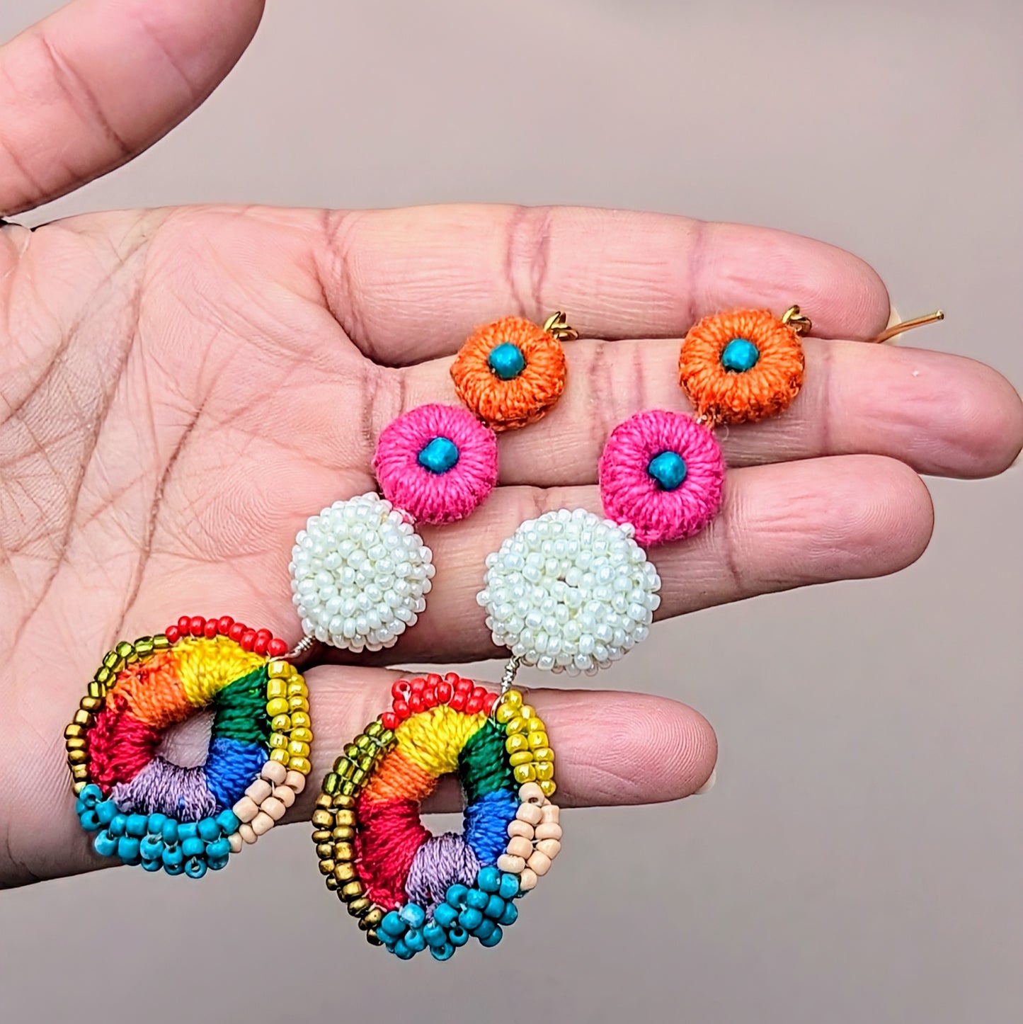 Bohemian rainbow earrings handmade using recycled seed beads and vibrant crochet, styled flat against a neutral grey background - part of Mayaani's signature one-off designs.