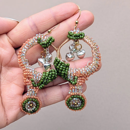 Close-up of Lakshmi statement handmade Indian beaded earrings with peach and green seed beads, silver ghungroo bells, and rose-gold wire, designed by Mayaani Jewellery UK.