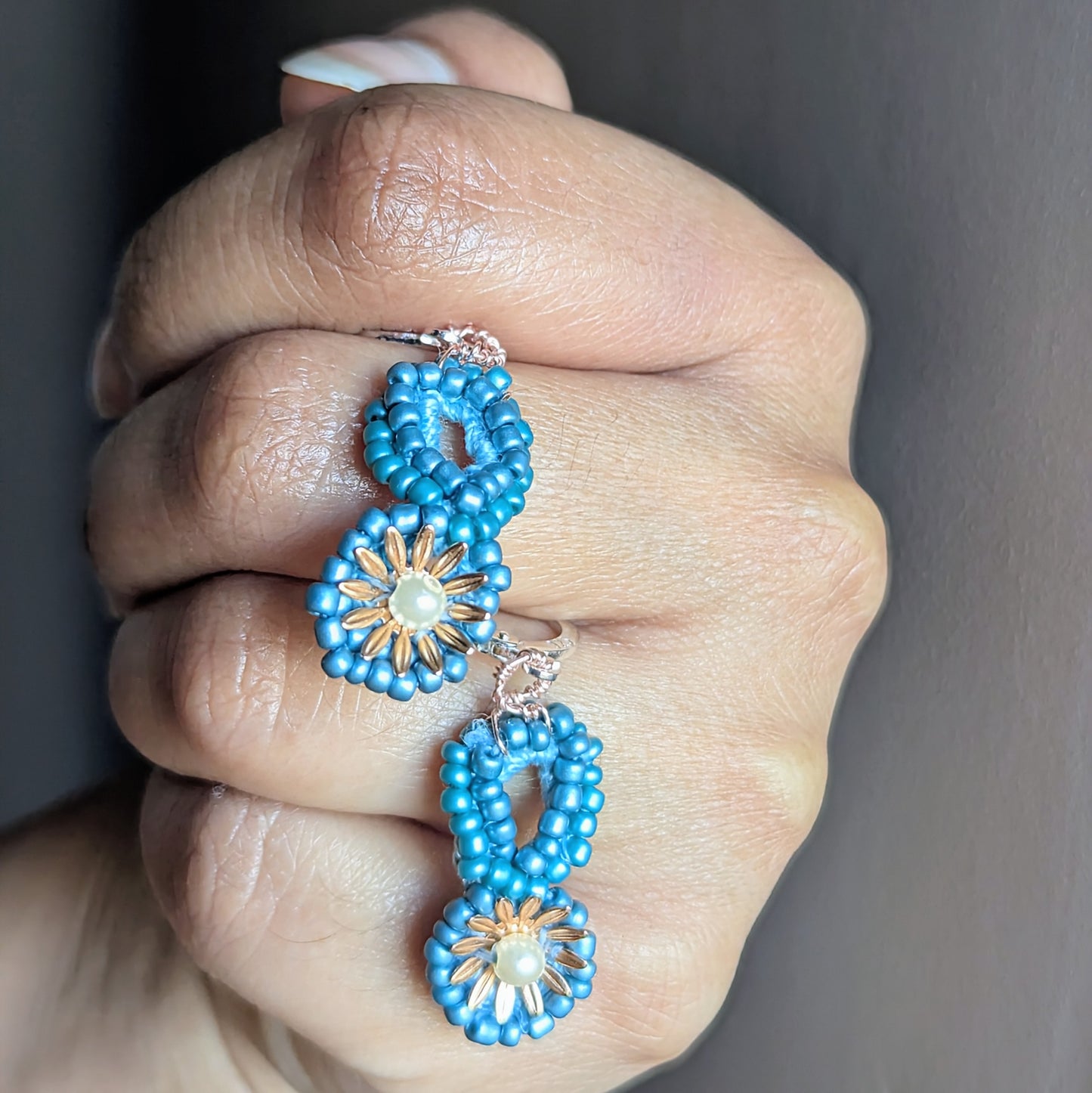 Handmade Tara earrings gently held in hand revealing fine embroidery and upcycled materials.