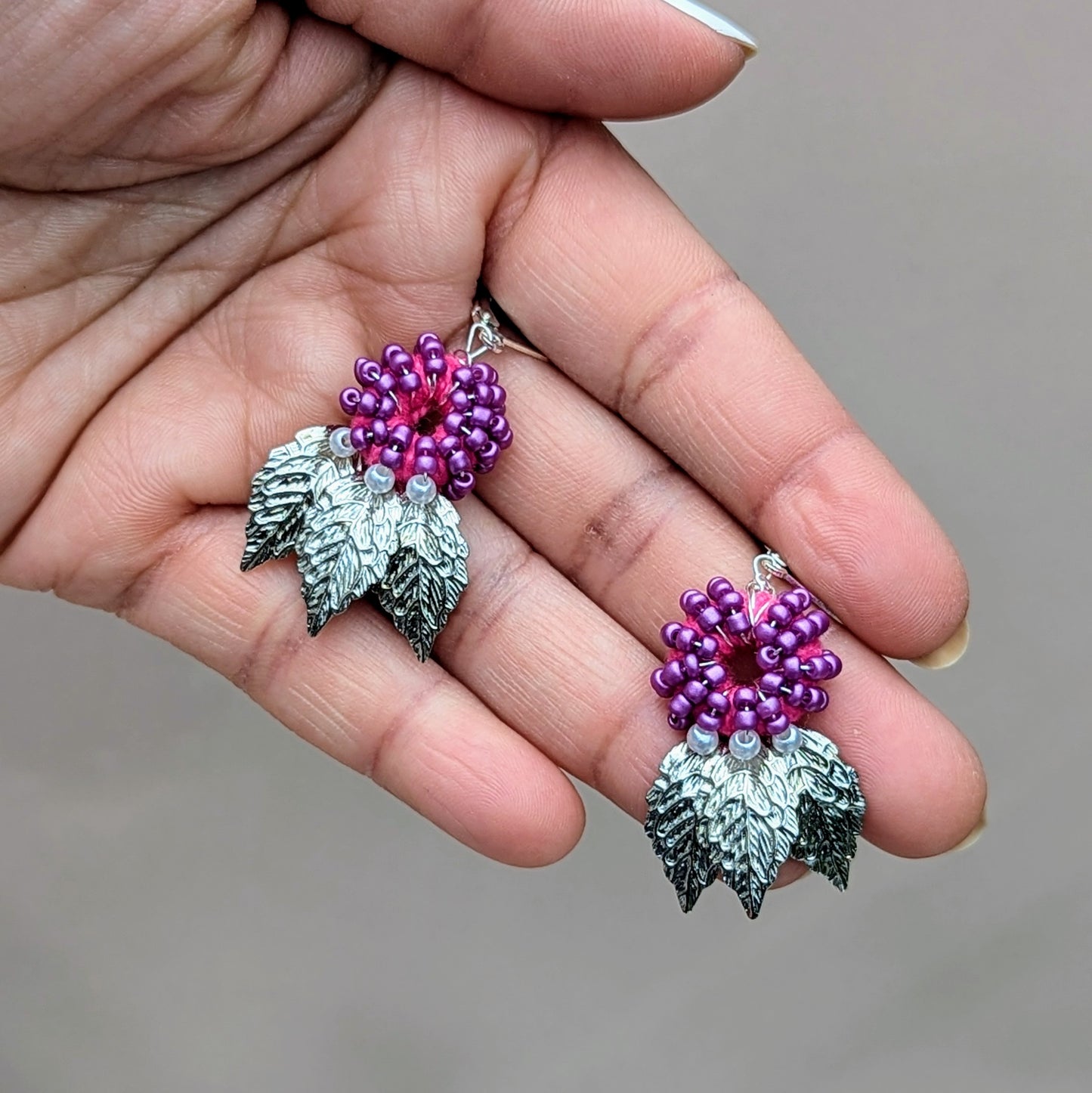 Lightweight handmade purple earrings inspired by floating leaves, photographed held in hand.