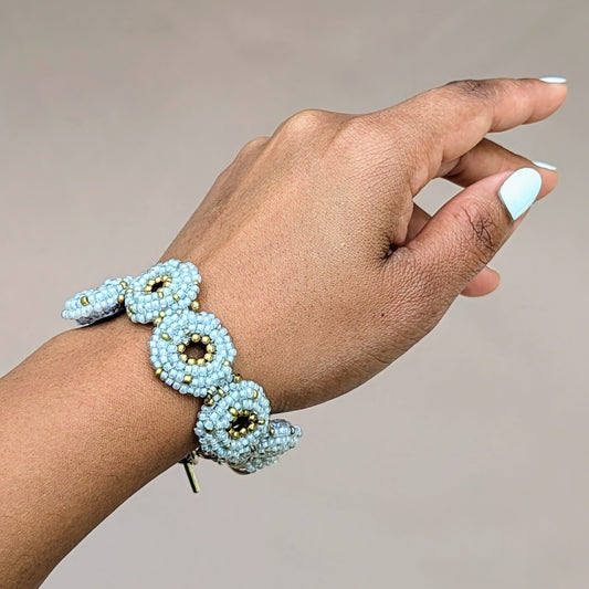 Elegant handmade bracelet with pale blue-silver tones and warm gold detailing, sustainably made in the UK.