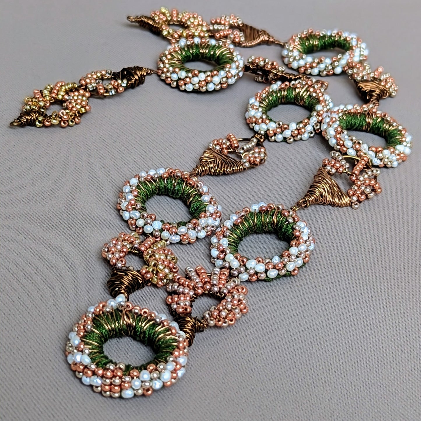 Decorative statement Indian style necklace with circular beads handcrafted in green, white, and bronze featuring 175 natural freshwater pearls.