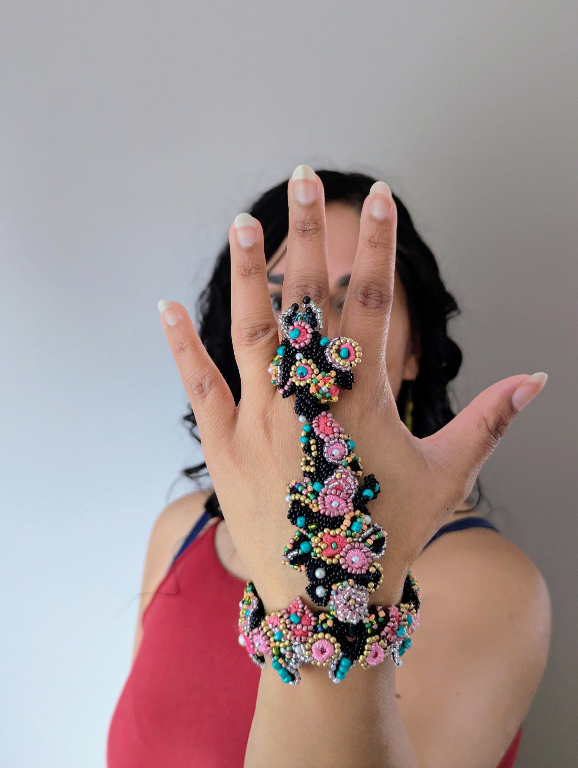 Model wearing the Madhuri 5-in-1 Indian hand bracelet in black, pink and blue with gold and ivory pearl accents exclusive to Mayaani Jewellery UK.