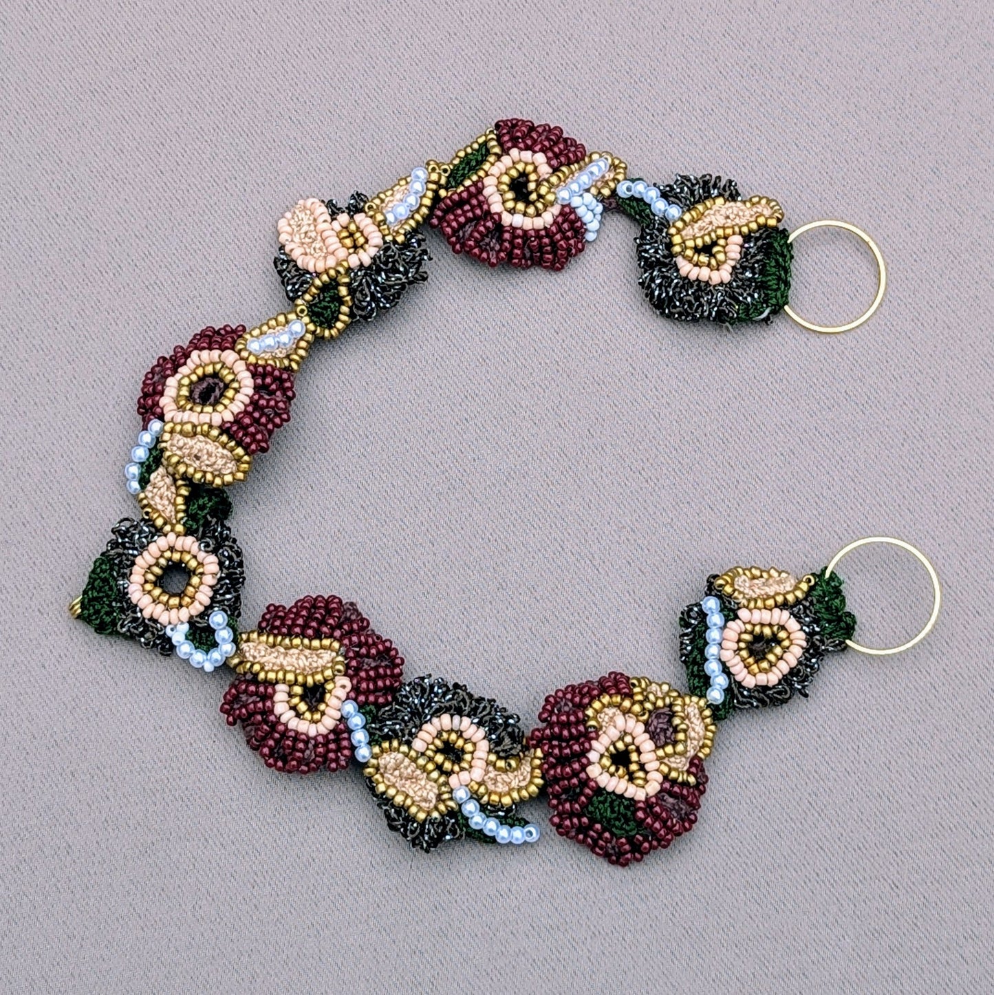 Flat lay view of the detached headband element of the Aishwarya Indian green, red, gold and pearl head piece exclusively crafted by Megha of Mayaani.