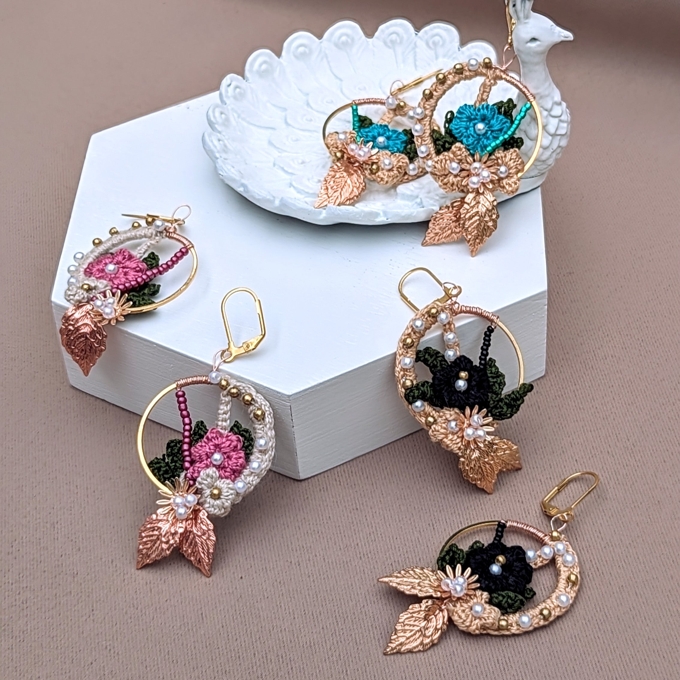 A trio of unique one of a kind, Indian inspired, lightweight, earrings featuring a gold hoop for a modern sophisticated aesthetic exclusive to sustainable UK brand Mayaani Jewellery. Enjoy one of a kind colours with only one pair of each colour available. Choose from delicate floral crochet motifs in a medium pink, turquoise blue or striking black tone, each of which is intricately hand woven with white seed pearl and solid brass beads, rose gold or gold leaf accents and meticulous hand wire wrapping. 