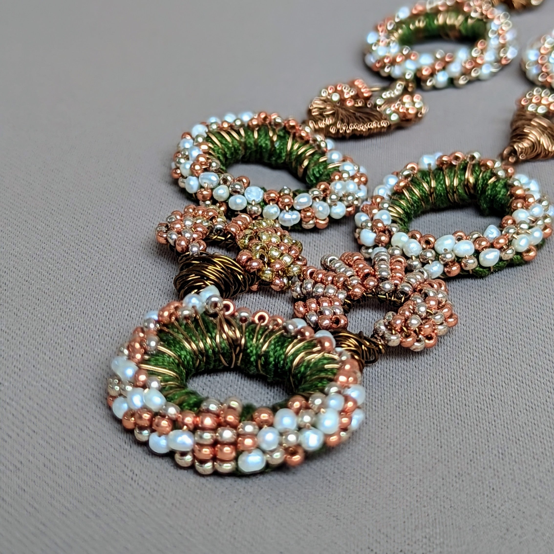 A unique one of a kind hand crochet hand wire wrapped natural freshwater ivory pearl, green, rose gold, gold and bronze statement Indian inspired necklace exclusive to sustainable brand Mayaani Jewellery UK and UK Indian designer and artisan Megha. Experience the joy of lightweight luxury jewellery designed in celebration of your individuality.