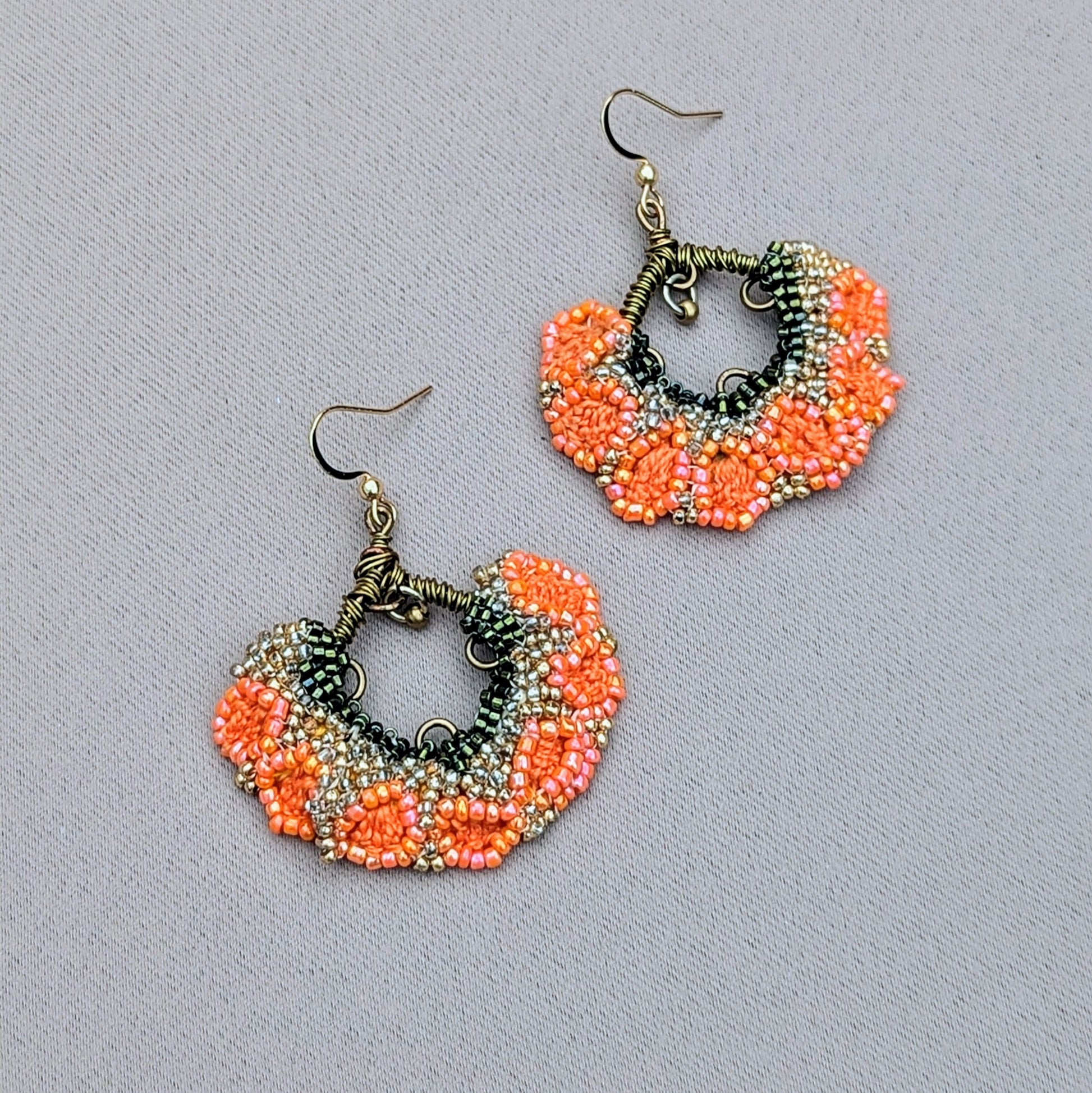 A bright bold beautiful orange green and gold pair of Indian earrings exclusive to sustainable UK brand Mayaani Jewellery. Featuring a small brass bead dangling beautifully from hand wrapped bronze copper wire work creating joyful movement within the movement of the floral fan like design. Pure joy for your special occasions through to everyday.