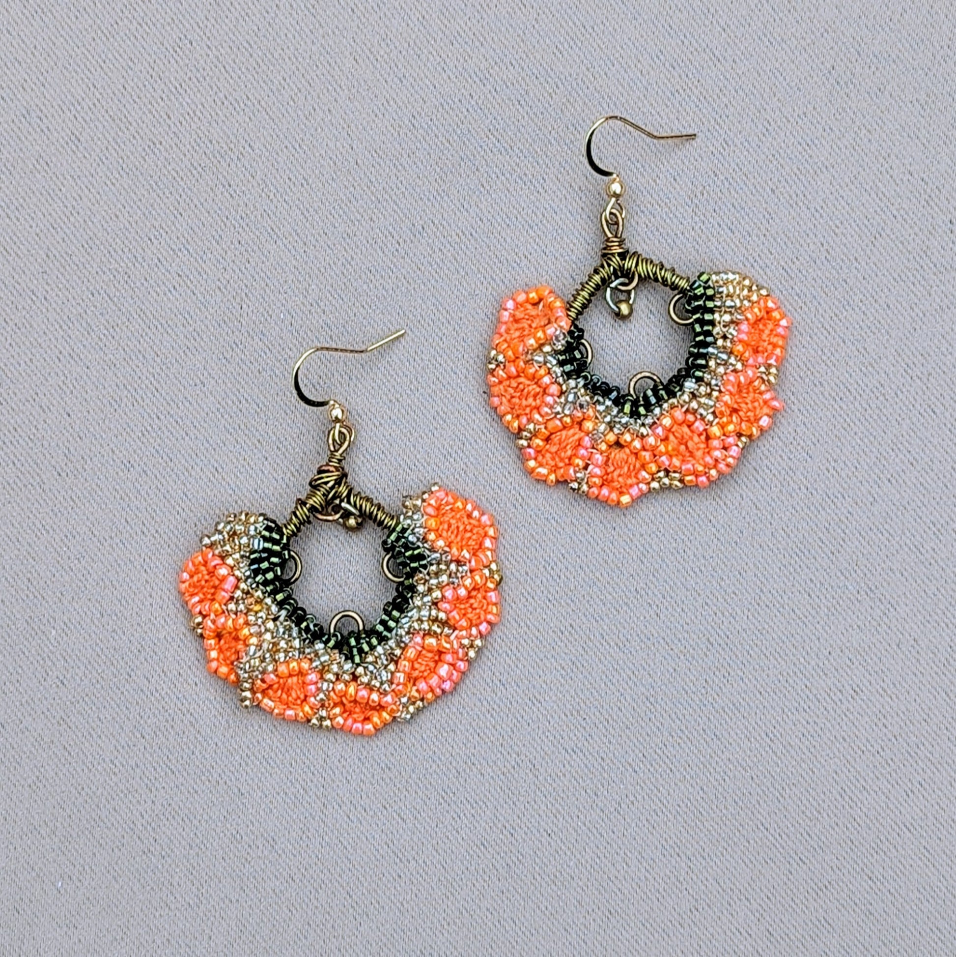 Brighten your collection with these beautiful orange, green, and gold Indian earrings, exclusively from the sustainable UK brand Mayaani Jewellery. A delightful brass bead dangles from intricately wrapped bronze copper wire, bringing joyful movement to the floral fan-inspired design. Perfect for special occasions or everyday wear, these earrings are a true expression of joy.