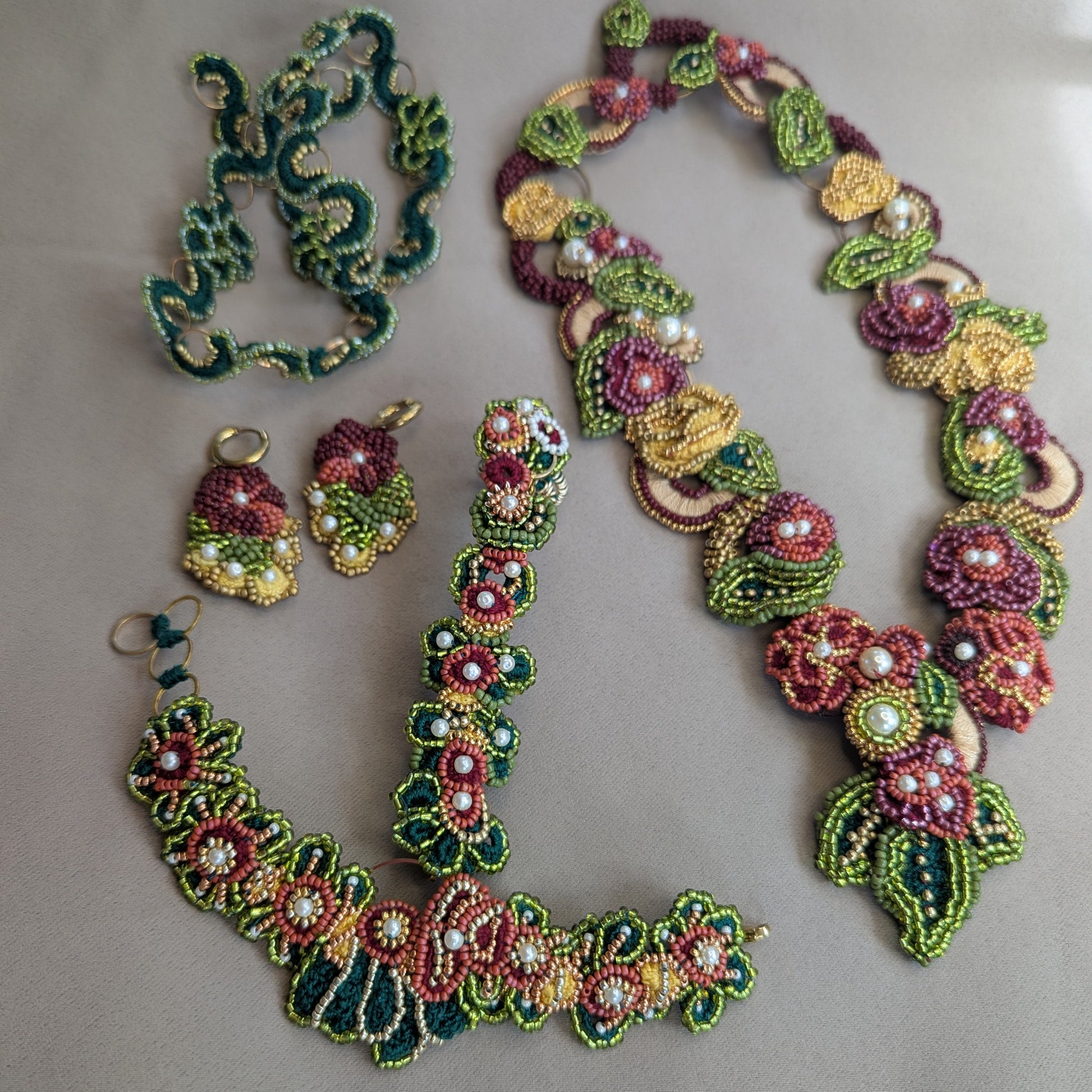 Flat lay of the innovative Rukmini couture Indian jewellery set in emerald green, olive green, gold, yellow 
and red featuring detachable pieces to seamlessly transition from occasion to everyday.