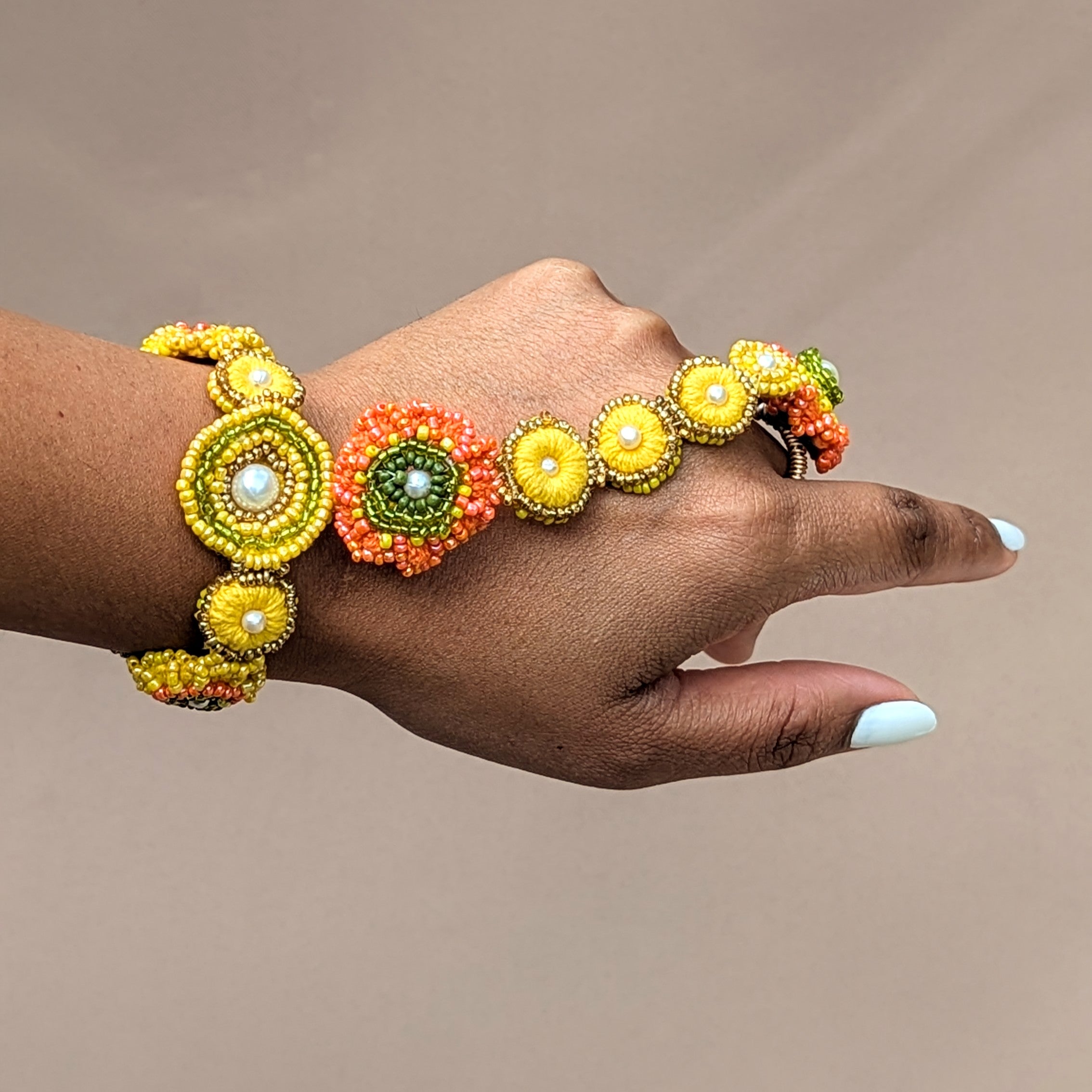 Hand modelling a yellow, orange and green haldi inspired Indian hand bracelet designed with versatility and comfort in mind. Exclusively available to Mayaani Jewellery UK this hand bracelet can be worn as a separate bracelet, ring and tikka.
