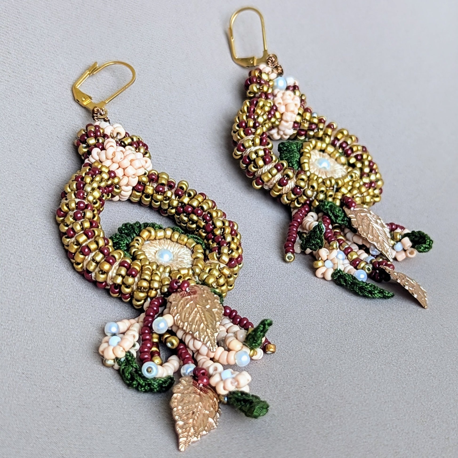 Side view of Aishwarya artisan handmade couture Indian bridal wedding occasion earrings in red, green, gold featuring gold plated leaves exclusively available at Mayaani Jewellery UK.