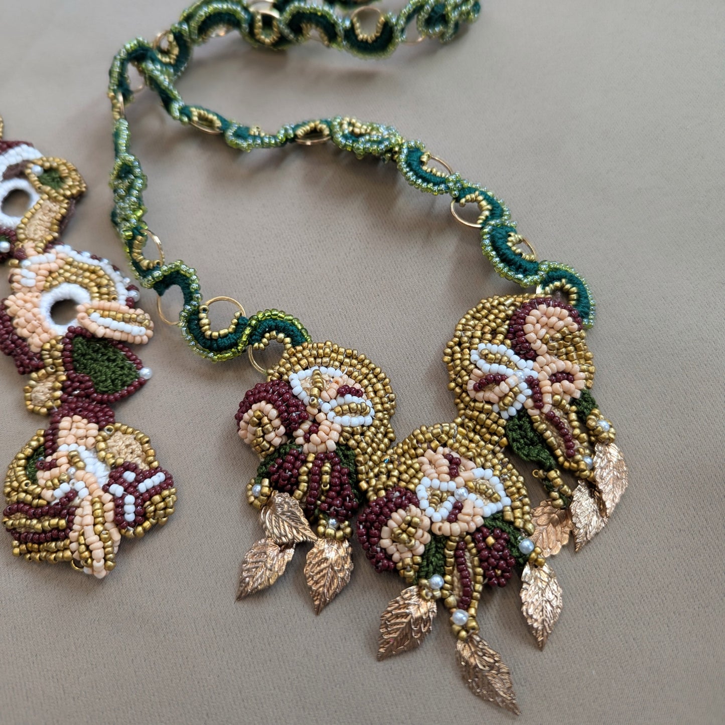 Close up view of the botanical inspired Aishwarya statement pendant with emerald green and gold custom chain exclusive to sustainable luxury brand Mayaani UK.