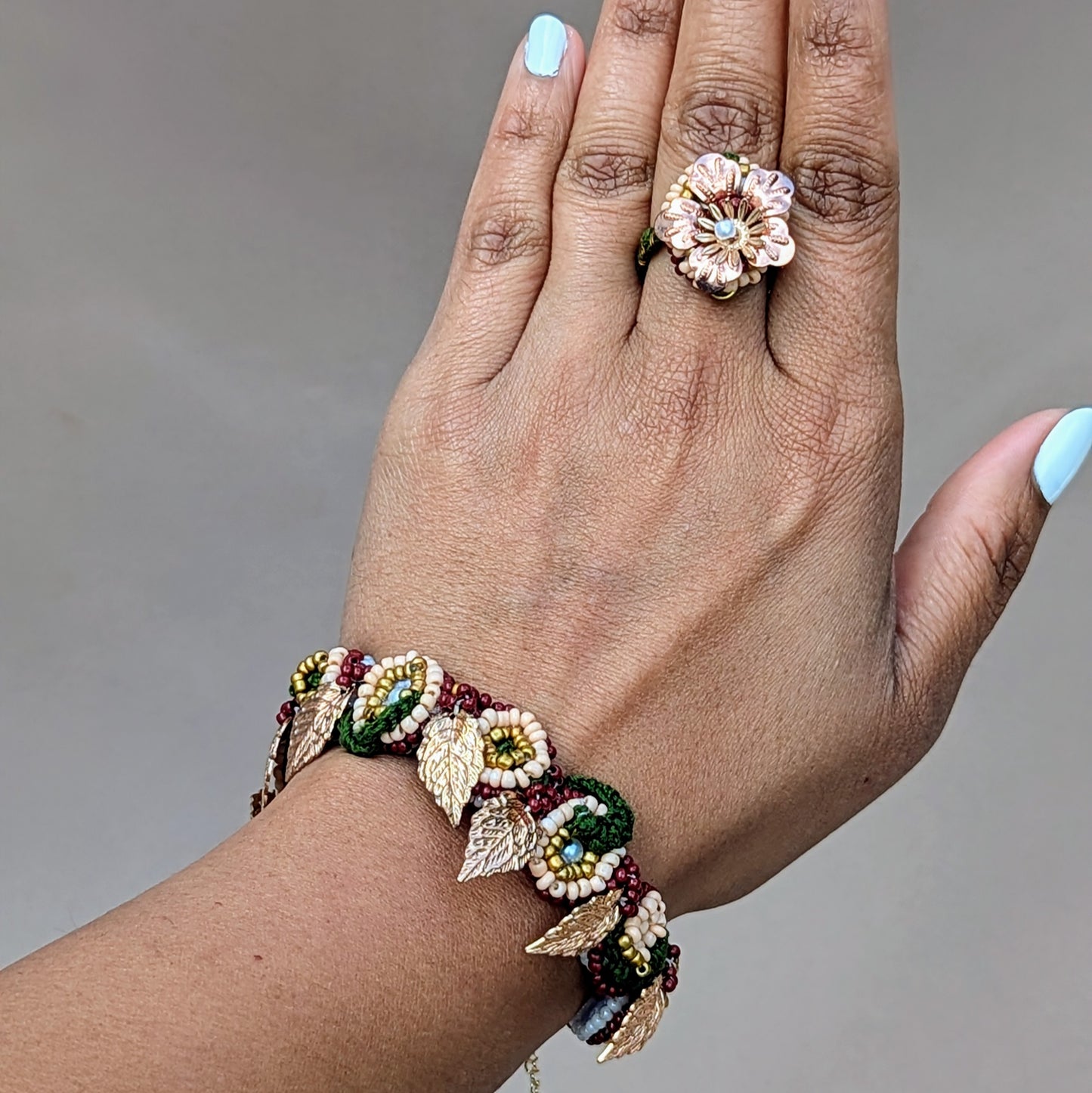 Hand modelled view of the Aishwarya intricately beaded red, green and gold bracelet and statement cocktail floral ring detachable from the Mayaani 3-in-1 Indian hand bracelet.