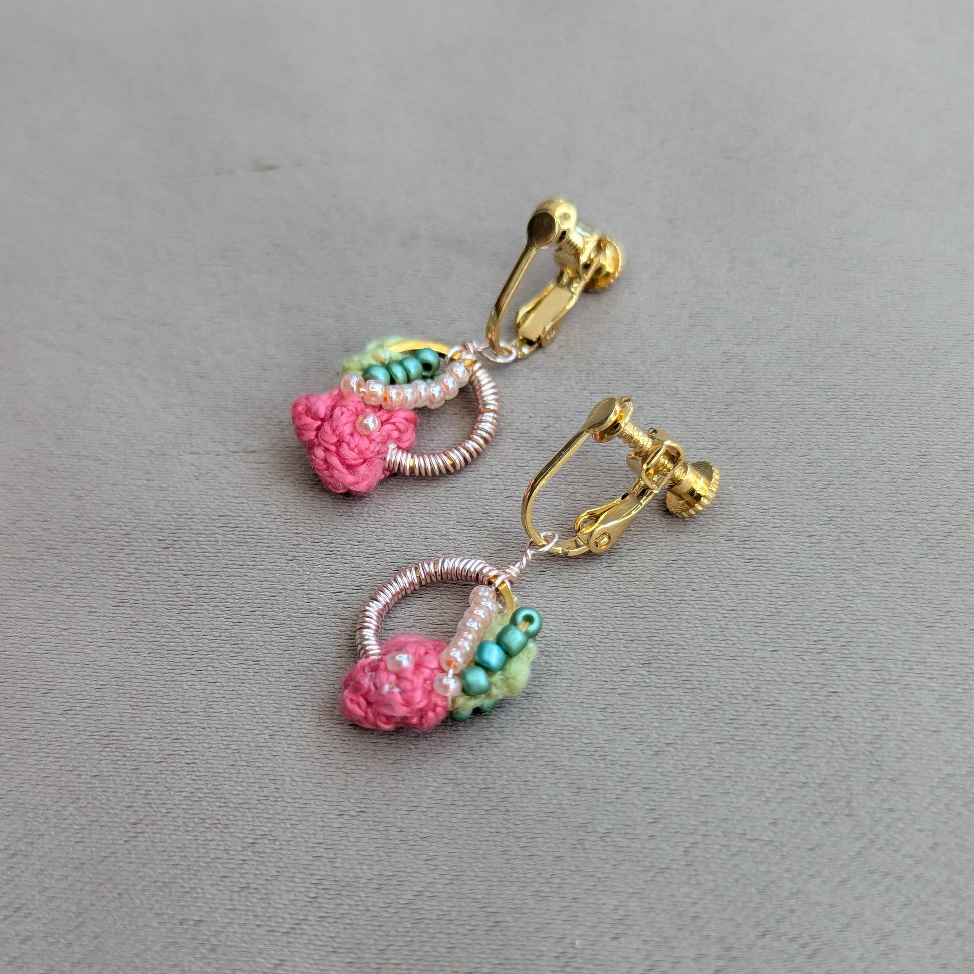 Flat lay of Anandi handmade pink, green and gold luxury clip-on earrings - one of a kind joyful luxury by UK indian designer and artisan Megha of Mayaani.
