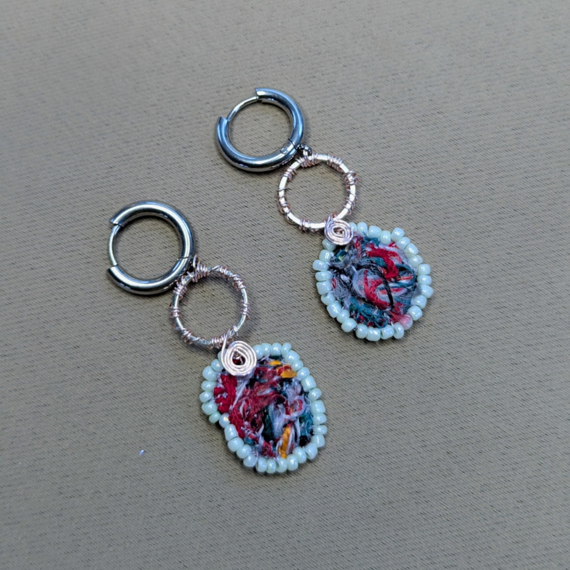 Flat lay of Anvaya handmade scrap bead earrings showing mint green glass seed bead edging.