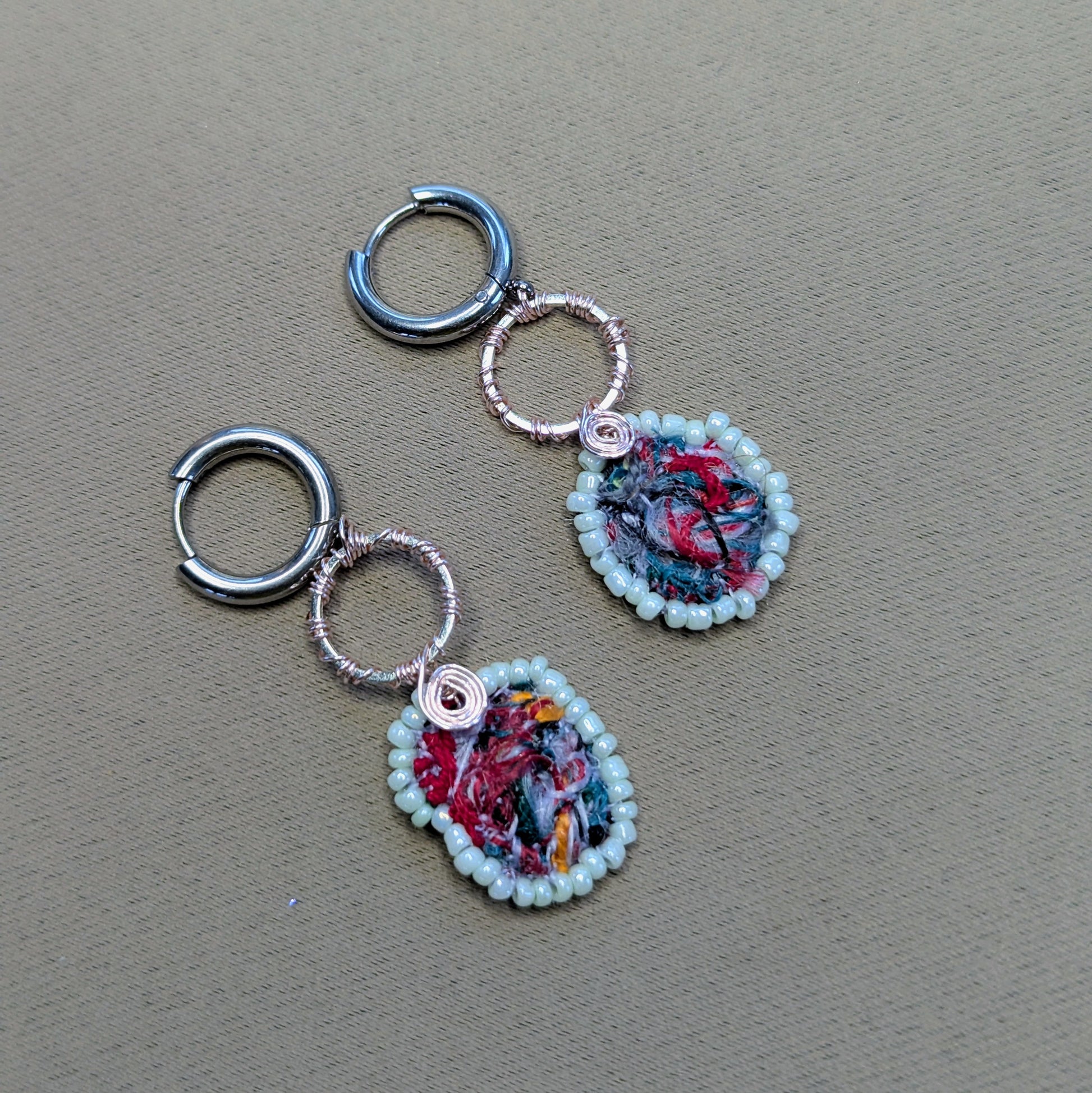 Artisan sustainable earrings with miniature abstract textile centres and silver-toned hoops.