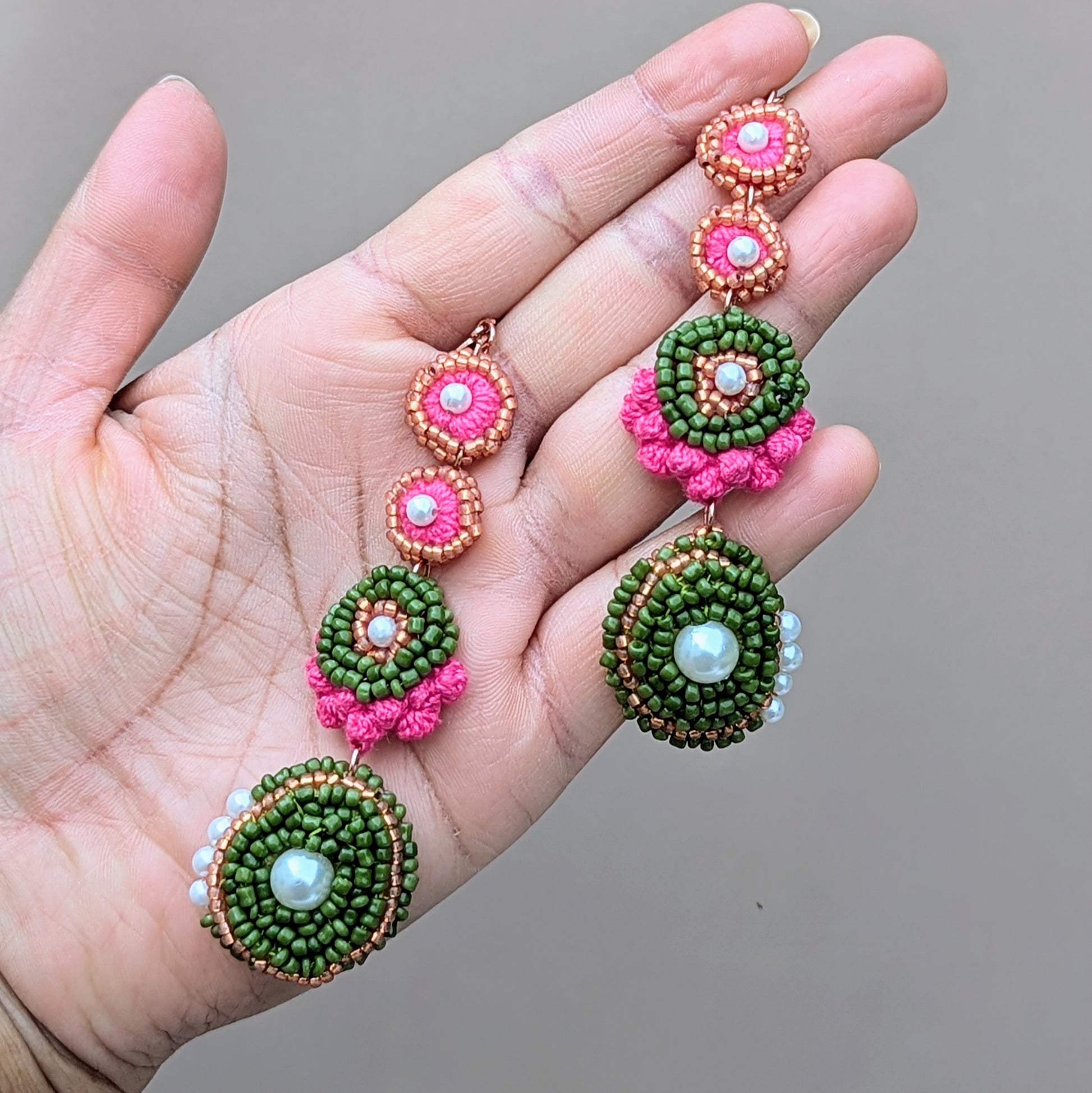Minna pink and pearl statement earrings held in hand, highlighting intricate bead embroidery, circular motifs, and sustainable artisan craftsmanship.