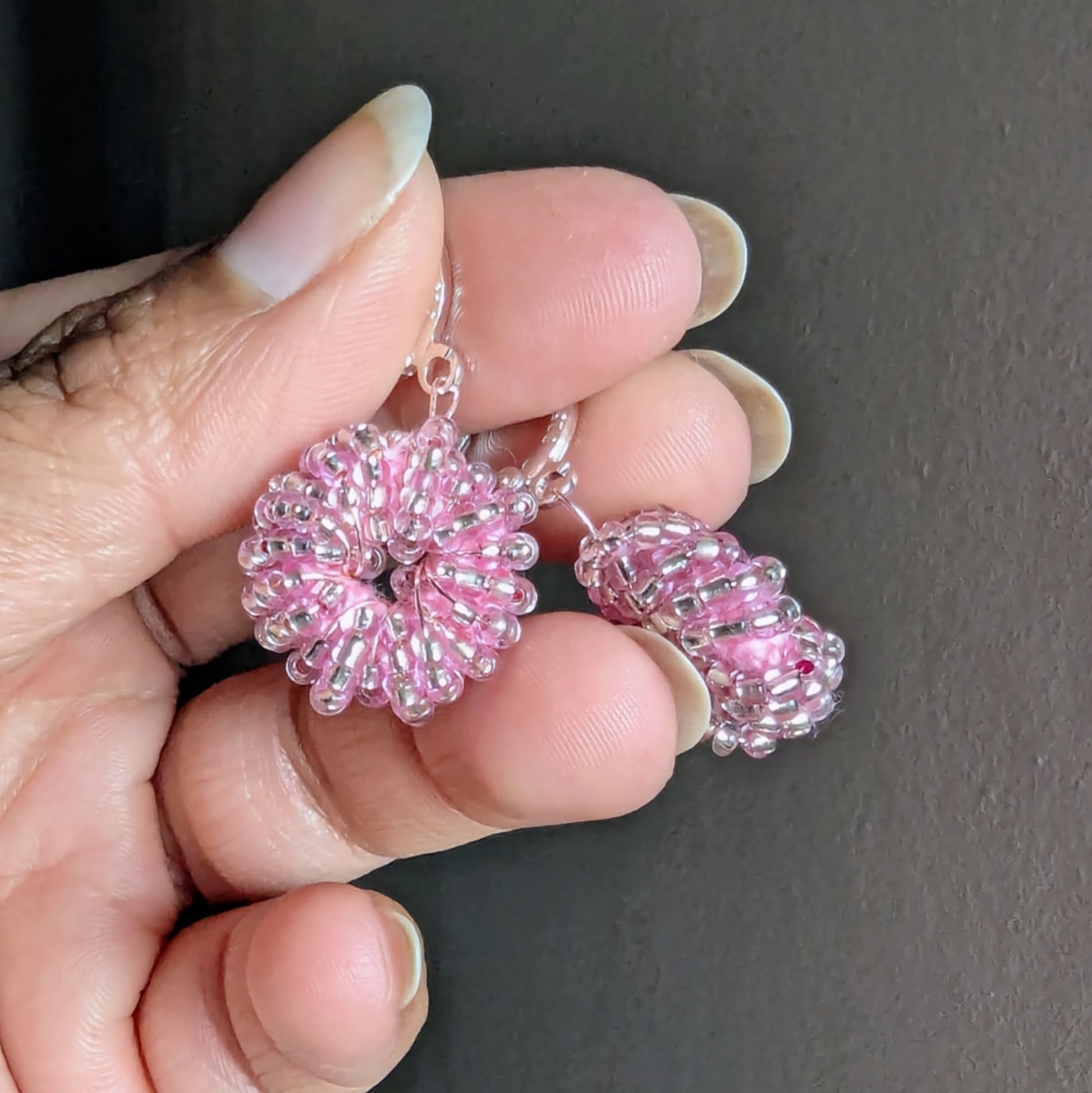Hand holding a pair of silver-lined pink handmade beaded earrings crafted by Mayaani Jewellery UK.