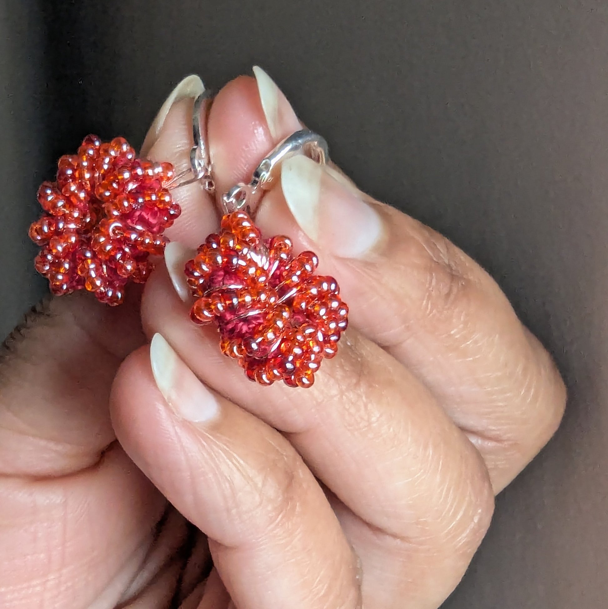 Close-up of fiery orange-red beaded earrings with sterling-silver clasps.