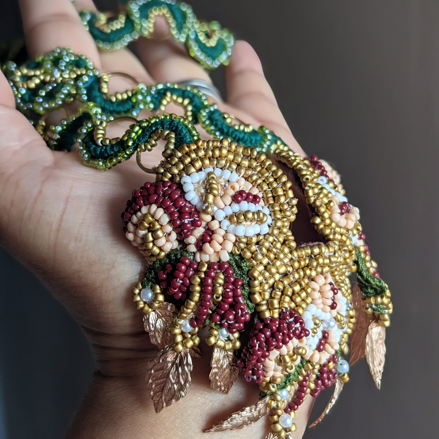 Close up view of the couture Aishwarya detachable pendant in red, green, gold and white attached to the Rukmini emerald green and gold chain custom made by Mayaani Jewellery UK.