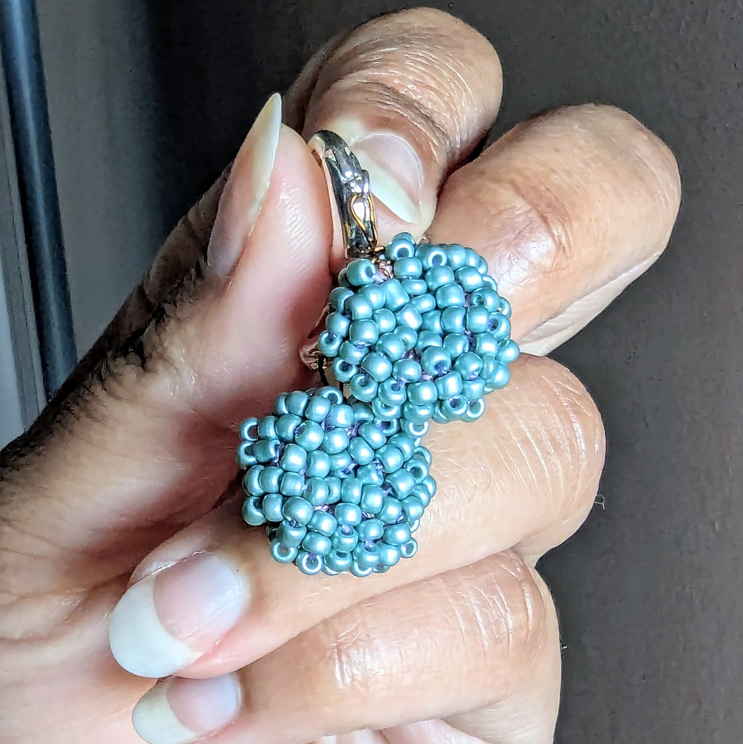 Close-up of Masi Nila earrings showing bead weaving and silver French clasp detailing.